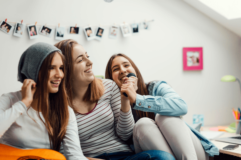 Teens Karaoke Party. - stock photo
Teenage Girls Having karaoke party together at slumber party. Sitting on couch and playing guitar and singing karaoke. Girls fighting for microphone and having fun. Shot with Canon EOS 5Ds 50mp. Selective focus to girl with microphone.