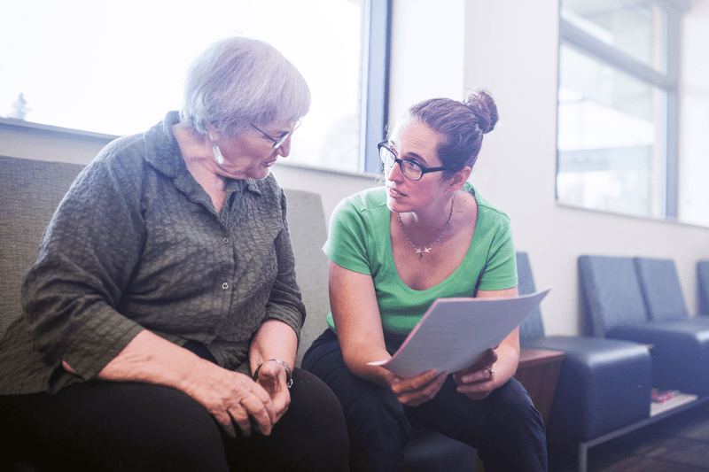 Senior Adult Woman Filling Out Paperwork - stock photo
A mature woman in her 70's fills out medical paperwork at the Dr. office for a routine healthcare checkup. A physician, friend, or daughter discusses the papers with the woman. Horizontal image.